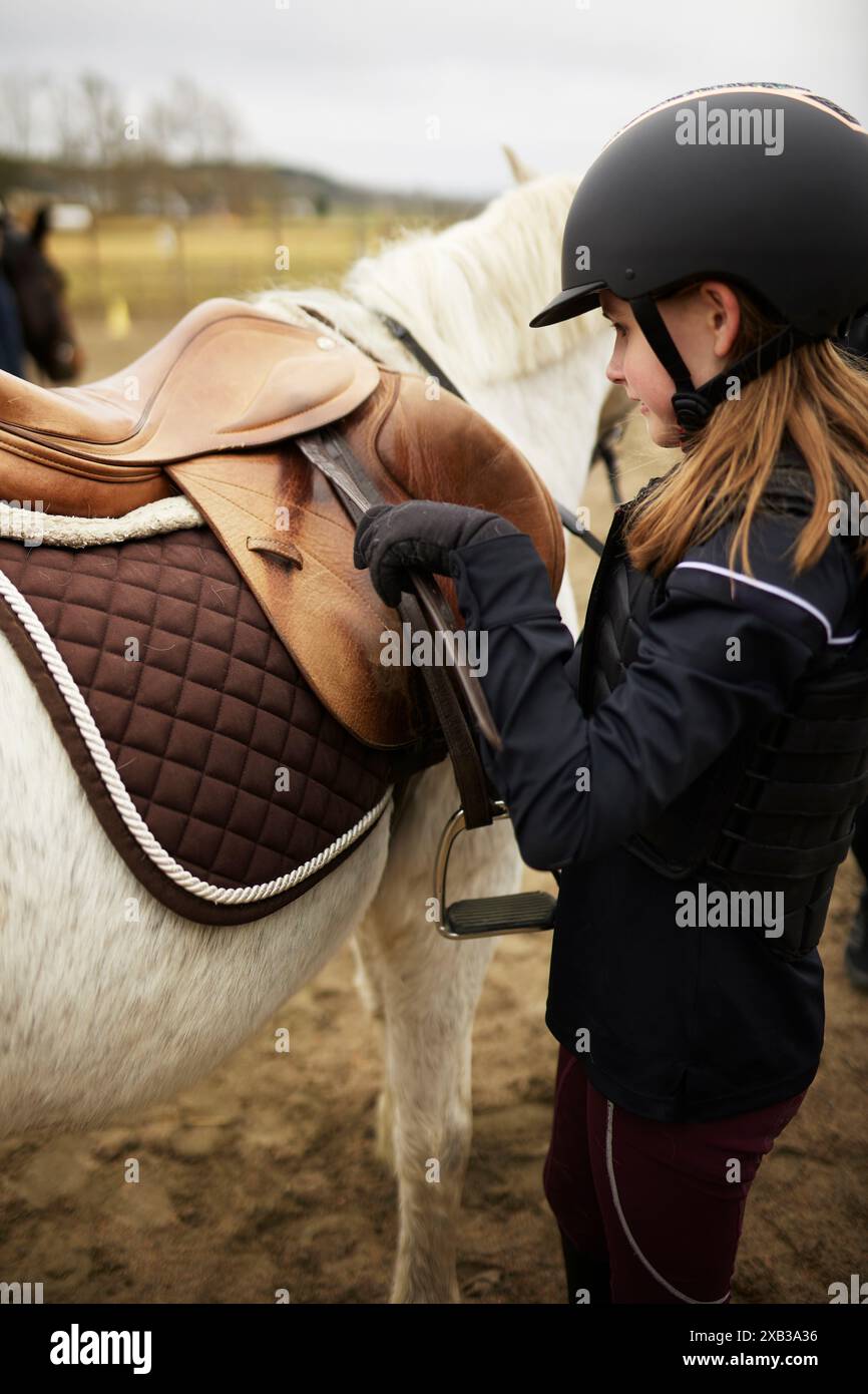 Girl wearing helmet standing with horse at ranch Stock Photo