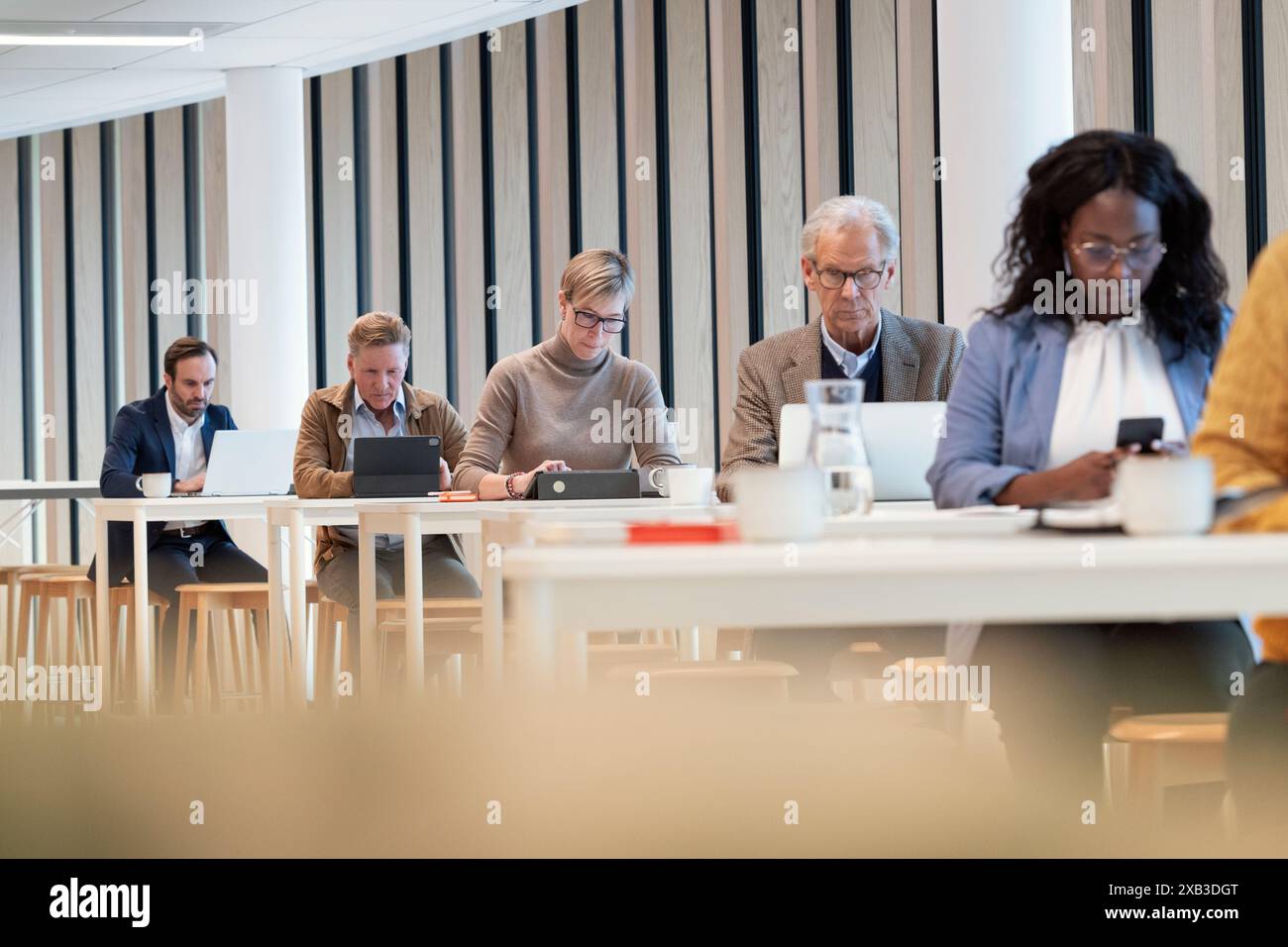 Multiracial colleagues using technologies in office cafeteria Stock Photo