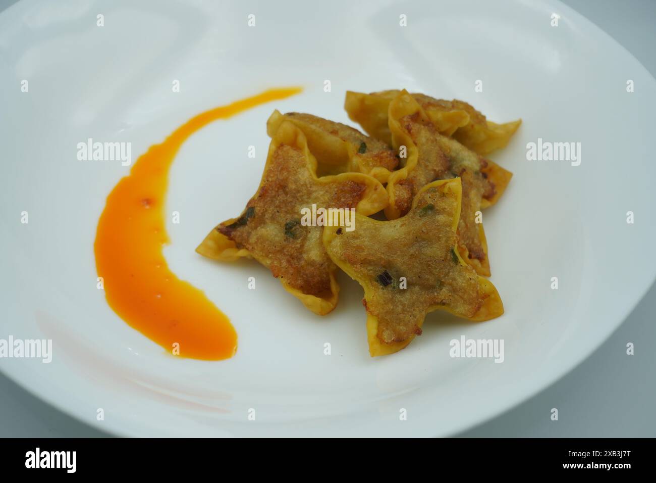 Fried dumplings with chili oil on a white plate with a white background Stock Photo