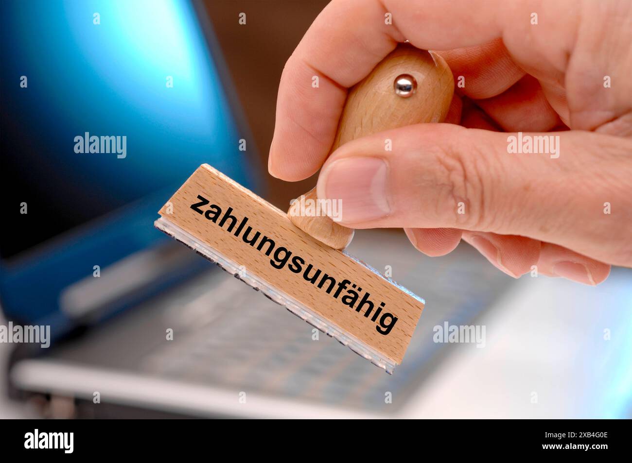 Zahlungsunfähig und Insolvenz Eine Hand hält einen Holzstempel mit dem Aufdruck - zahlungsunfähig *** Insolvent and insolvency A hand holds a wooden s Stock Photo