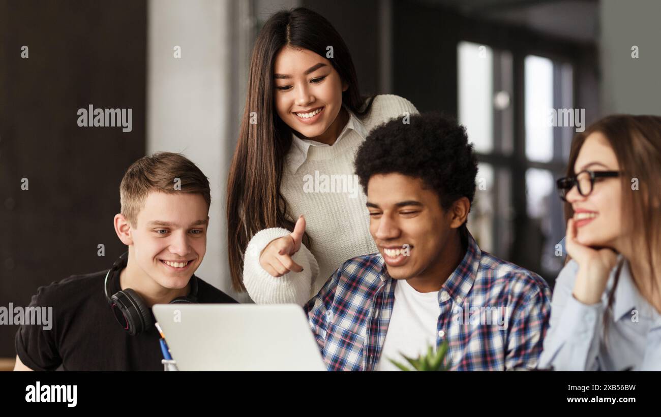 College students using laptop in library, studying together Stock Photo