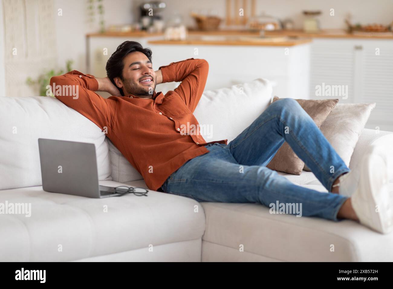 Relaxed Man Resting on a White Couch Stock Photo