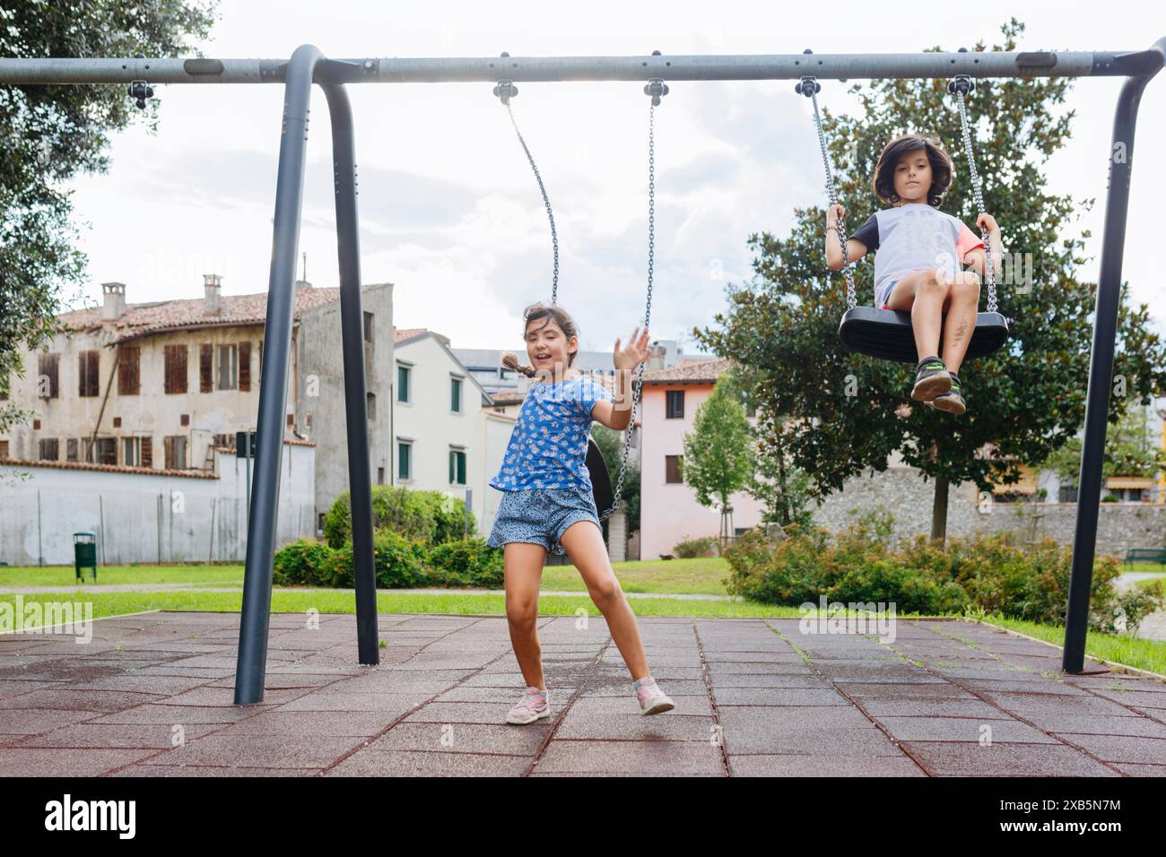 Two girls sitting on a swing at the playground Stock Photo - Alamy