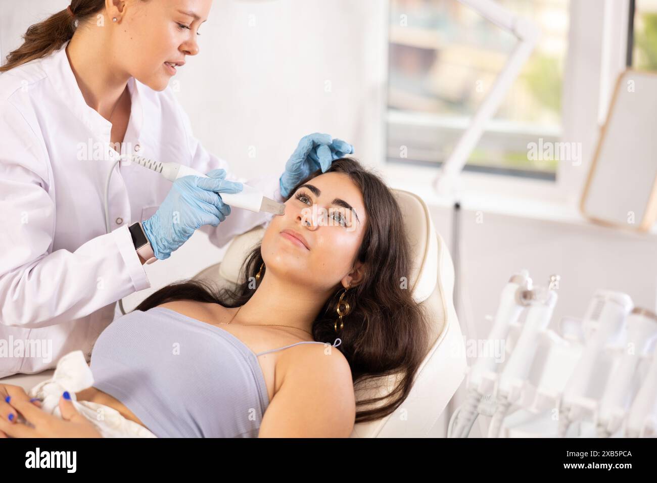 Young brunette undergoing hardware facial treatment using ultrasonic ...