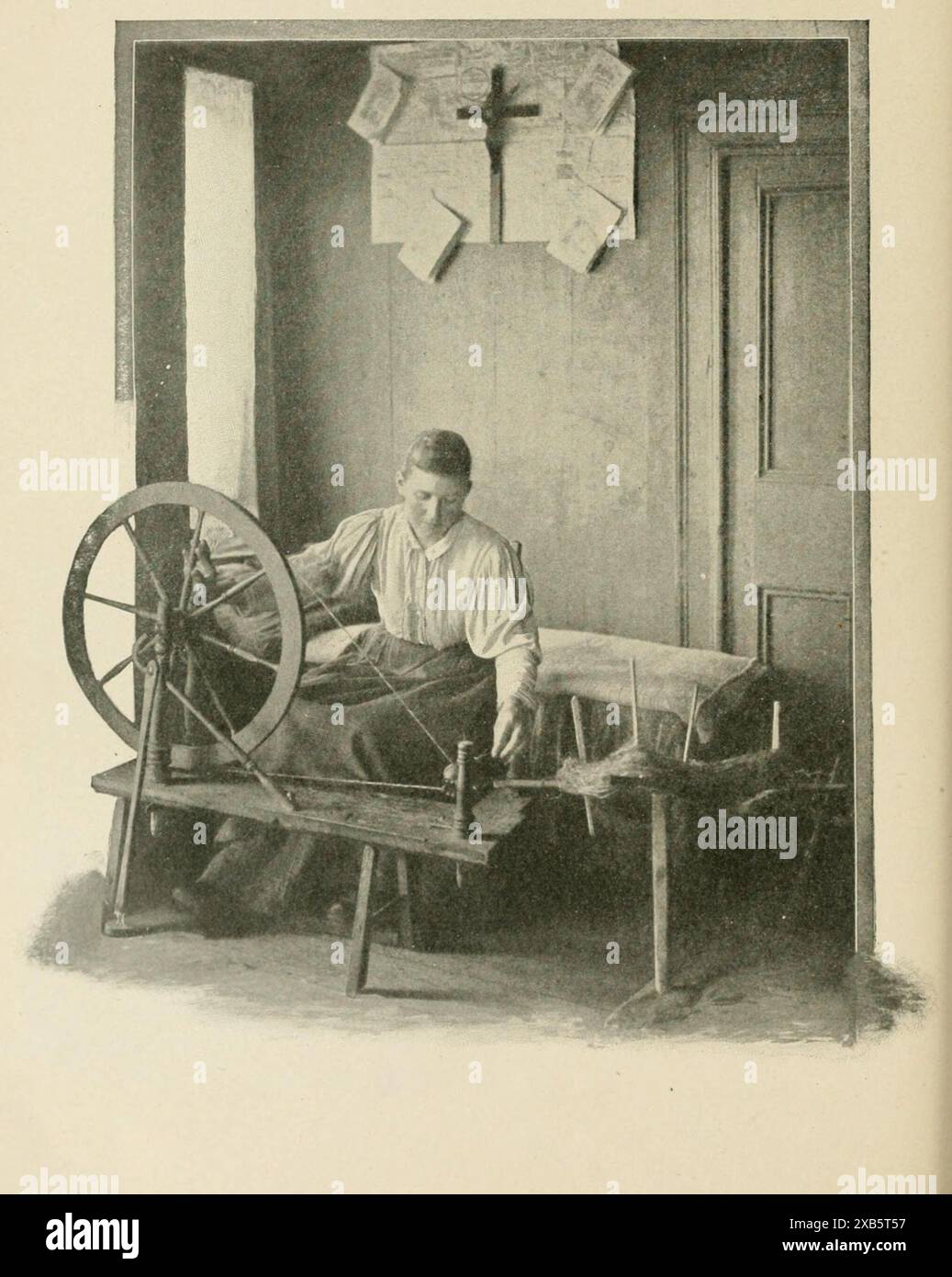 Vintage illustration of a woman using a spinning wheel to spin yarn or thread in a rustic setting, circa 1910s Quebec, Canada Stock Photo