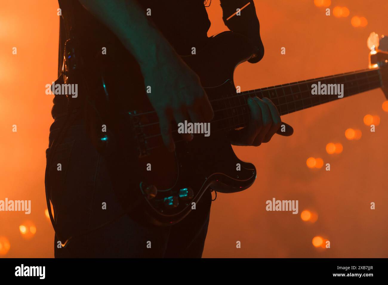 Electric bass guitar player silhouette in bright stage lights, closeup photo with selective focus Stock Photo