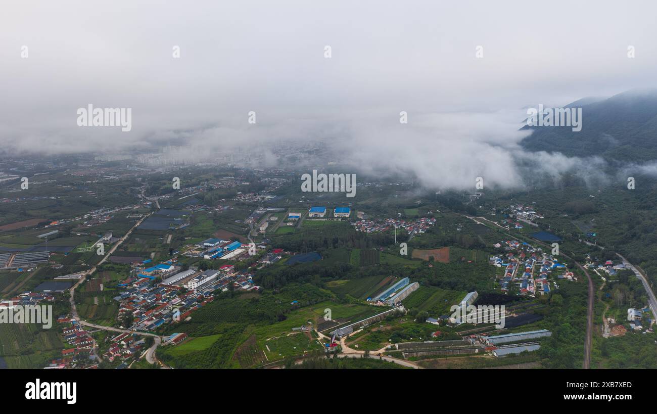 An aerial view of a town in green mountains on a foggy day Stock Photo ...