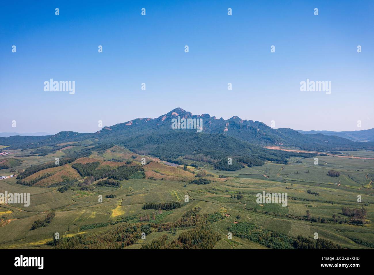 An aerial view of mountains covered with green forests on a sunny day ...