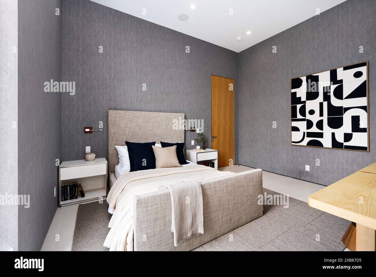 A modern bedroom featuring a spacious bed and wall art Stock Photo