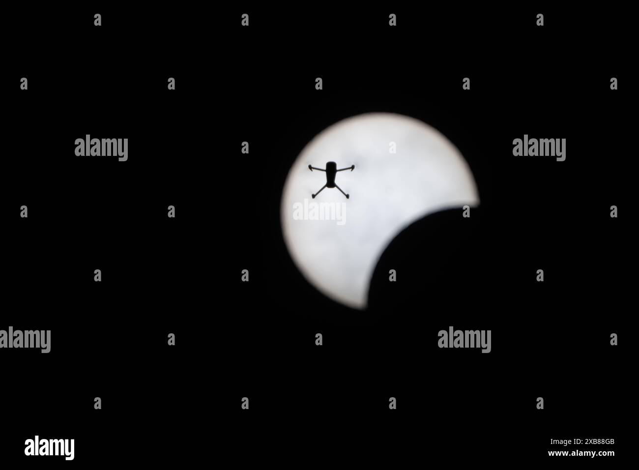 Silhouetted man flying in dark sky with sun backdrop Stock Photo