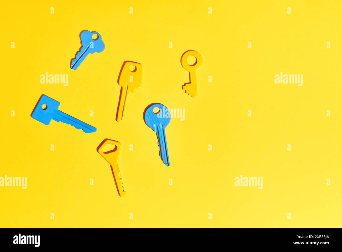 Various colorful keys on vibrant yellow background with copy space ...
