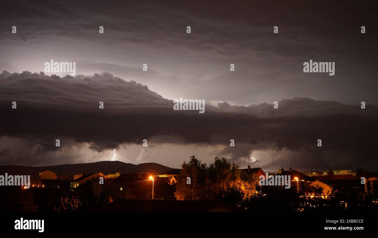 A dark stormy night sky above houses and mountains Stock Photo - Alamy