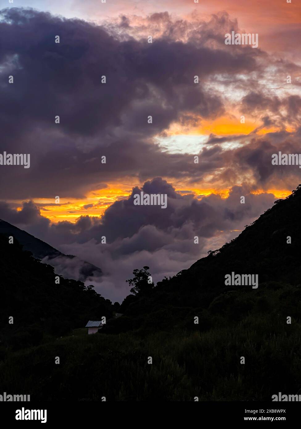 Dramatic sunset sky over mountain lake with dark clouds Stock Photo