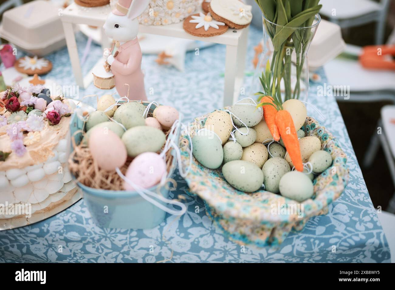 A table adorned with flowers, bunnies, and assorted Easter eggs Stock Photo
