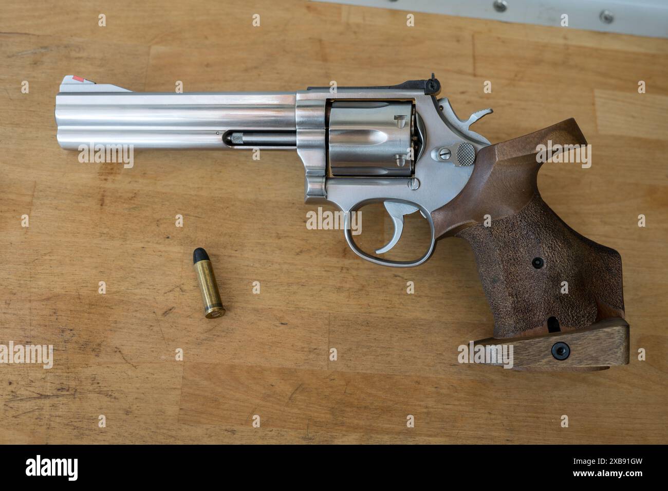 Detail of a revolver-type pistol on a wooden table, next to it there is ...
