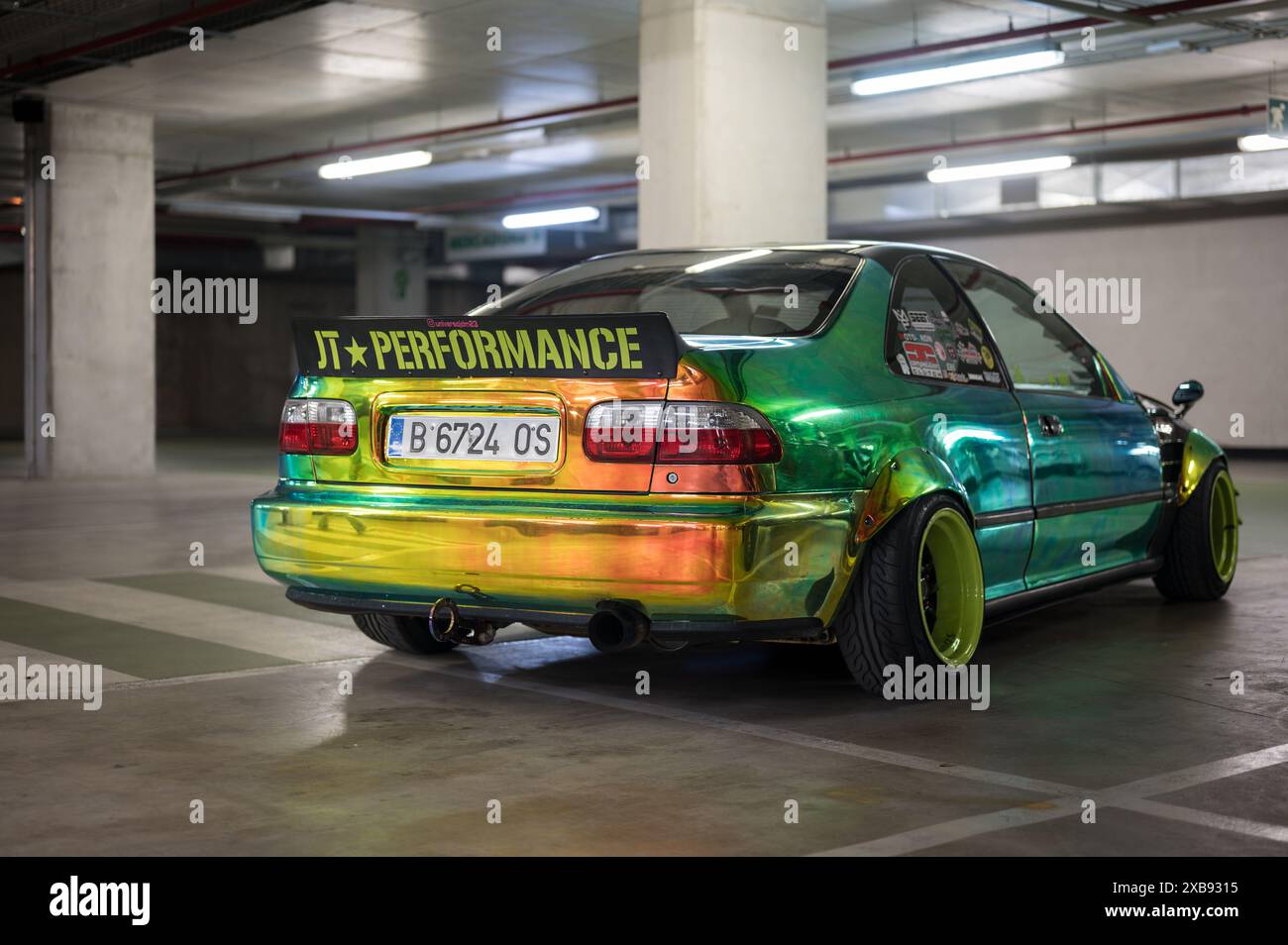 A rear view of the Japanese sports car tuned in JDM style Honda Civic EG8 Sedan painted in iridescent changing color parked in the parking lot Stock Photo