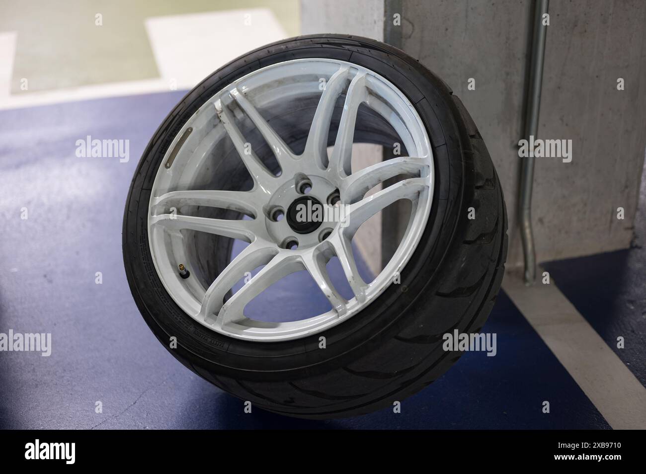 A sports car wheel resting on the pillar of a parking lot. It is a ...