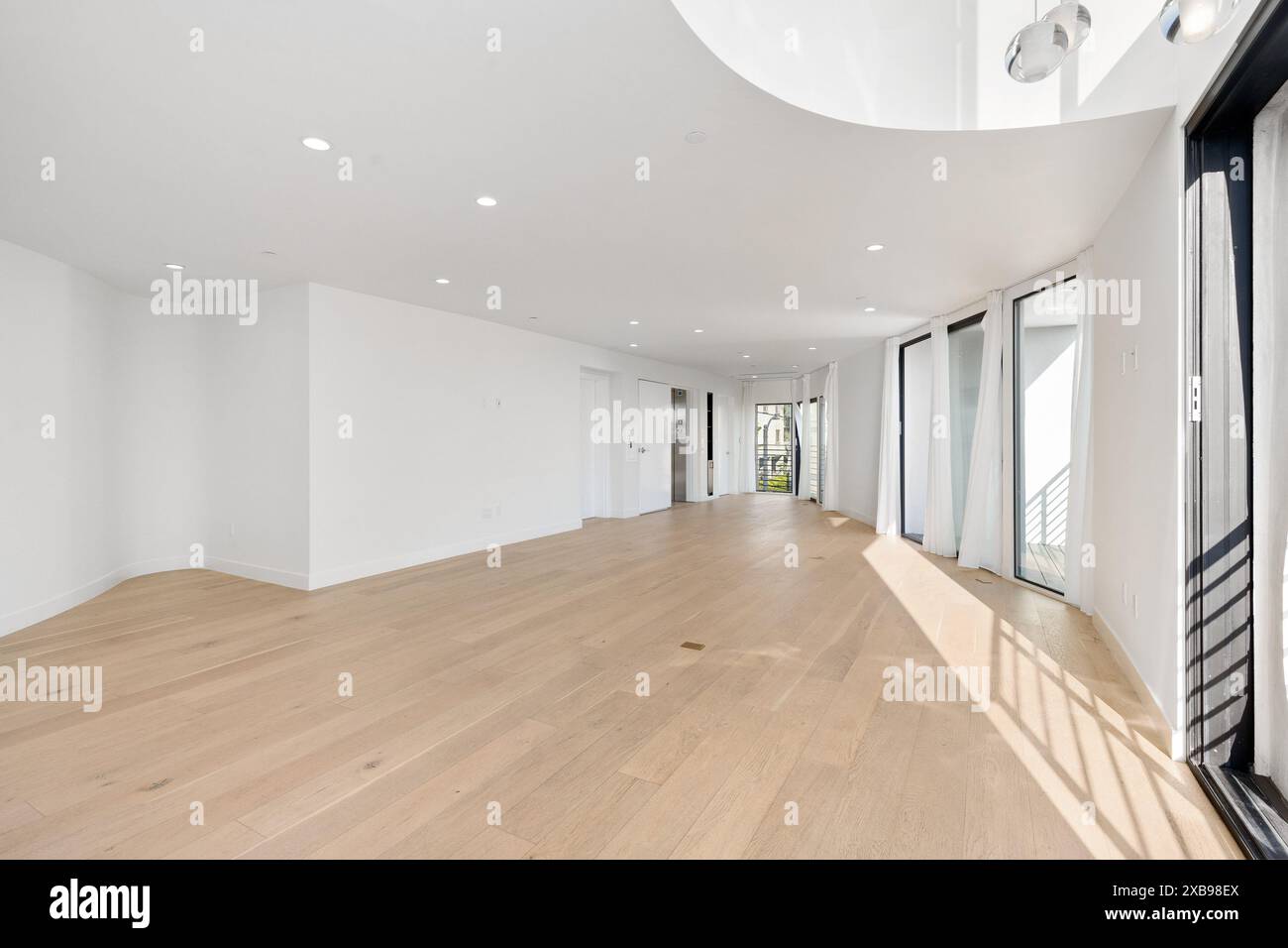 A spacious room with an open layout and light wood flooring. California ...