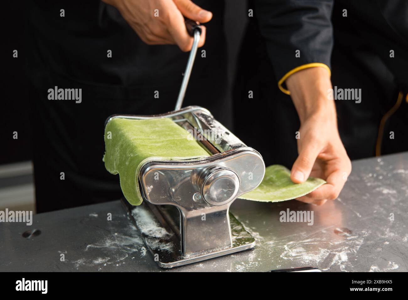 A Chef In Black Uniform Rolls Out Fresh Spinach Pasta Dough Using A A chef in black uniform rolls out fresh spinach pasta dough using a