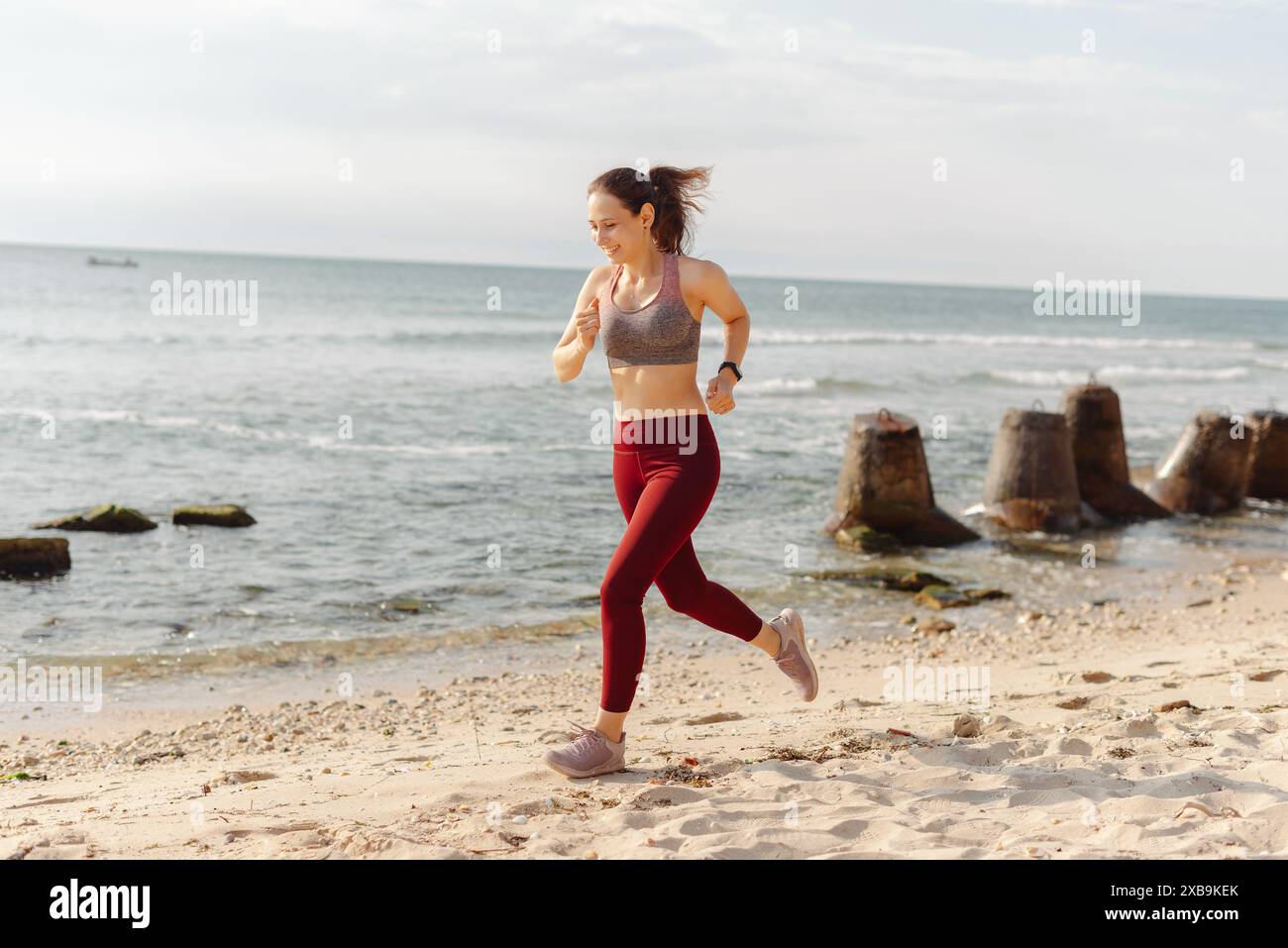 Woman in red leggings running along the beach. Clear sky and ocean ...