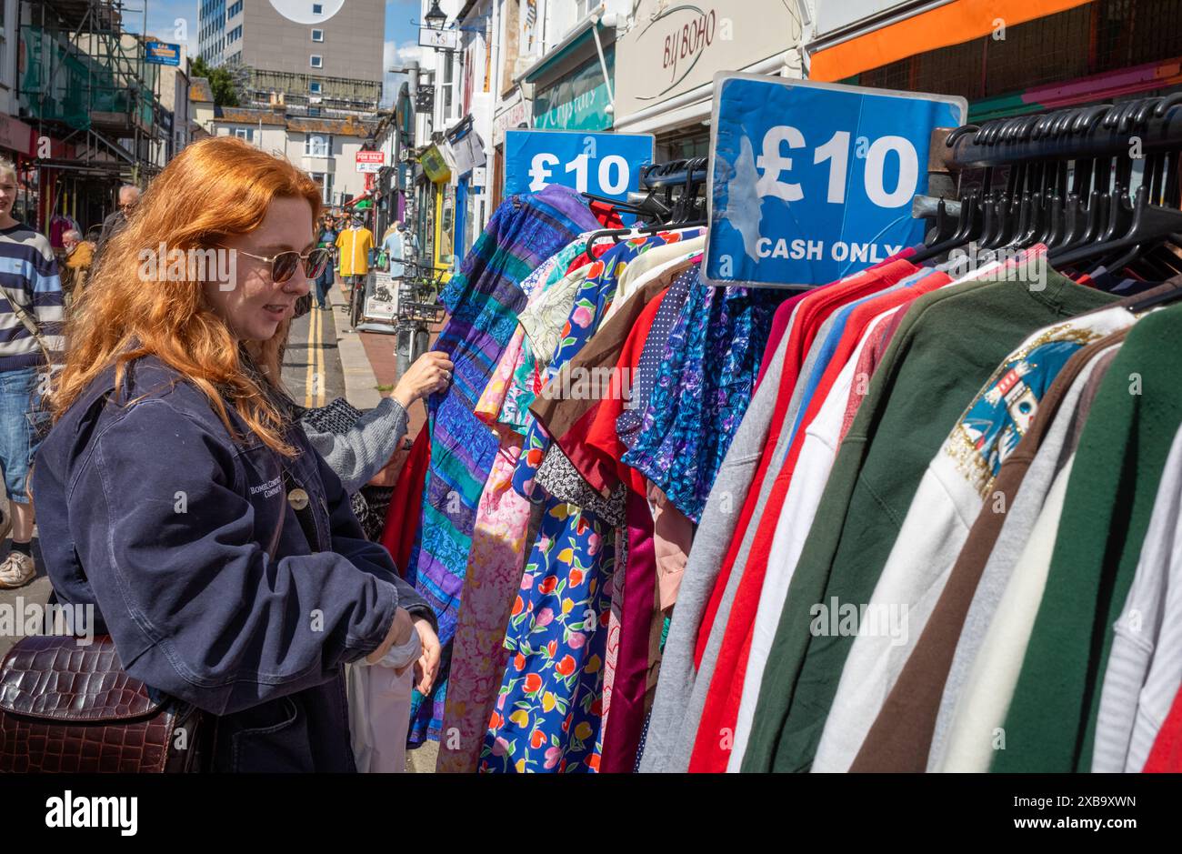 A woman browses second hand and vintage clothing for sale for £10 cash