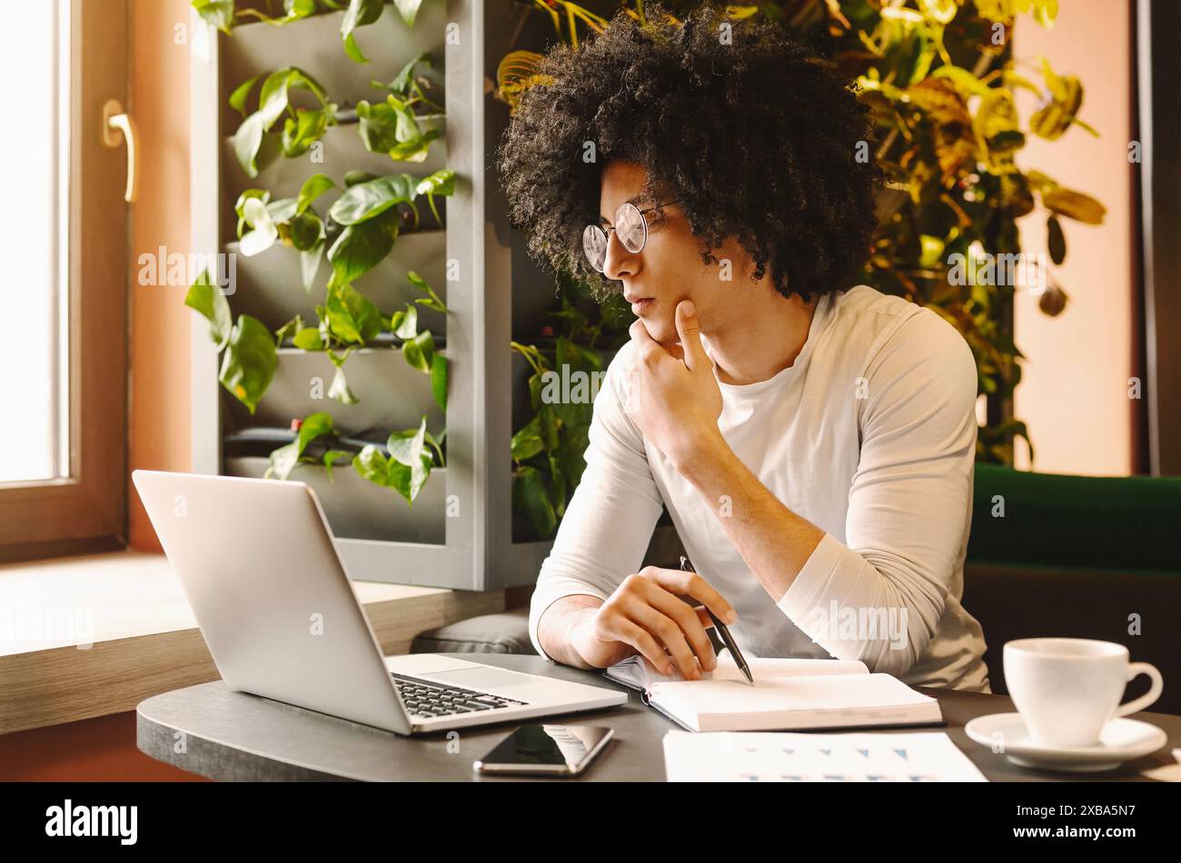 Confident young man working on laptop sitting in cafe Stock Photo