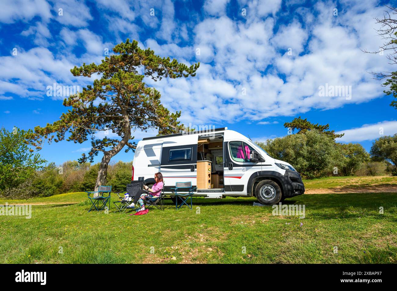 Woman In Rv Woman sitting in front of campervan or motorhome parked on the beach ...
