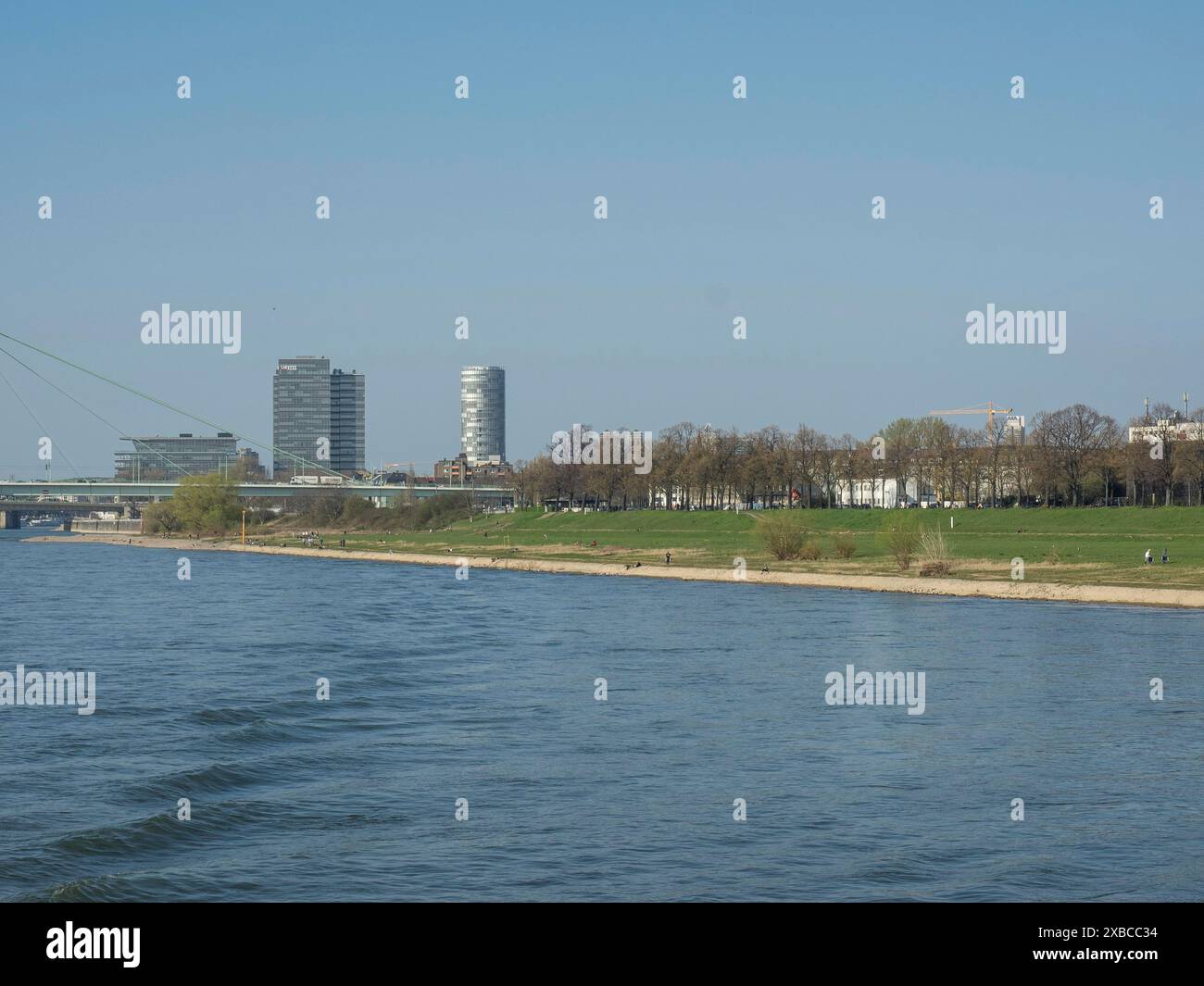 Riverside view with modern buildings, a meadow and trees in an urban ...