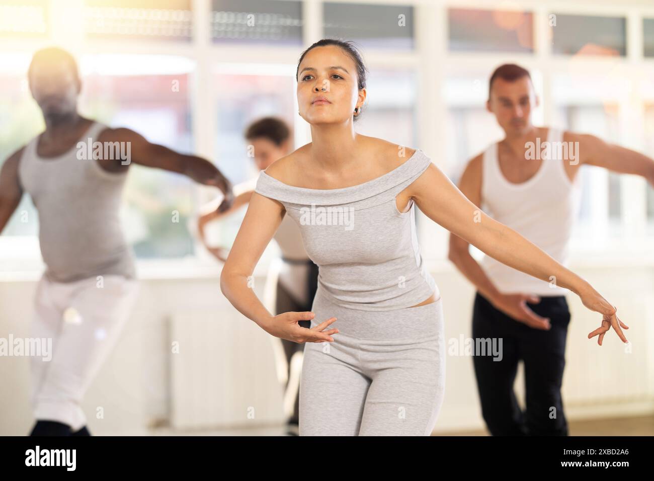 Young Asian woman practicing basic ballet movements at group class Stock Photo