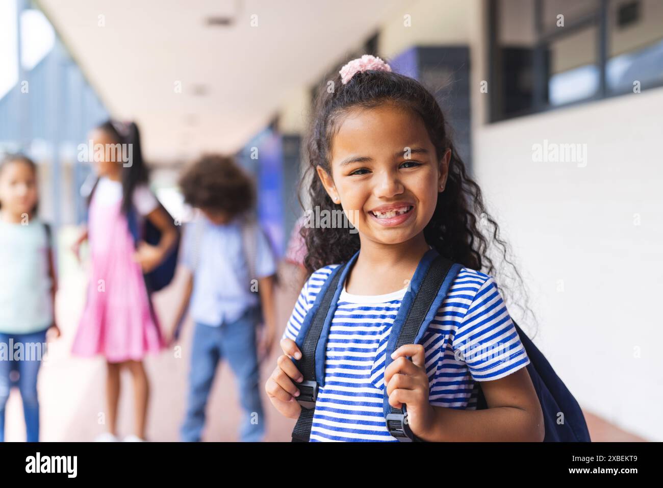 A group of biracial students is smiling and wearing backpacks in school ...