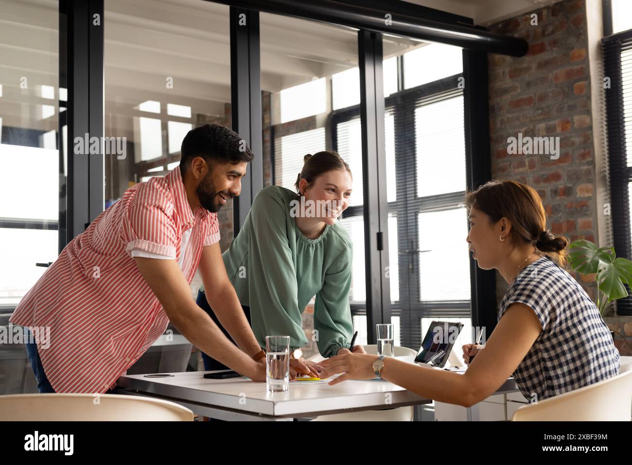 Unalt Diverse team collaborates; young woman and colleague share ideas ...