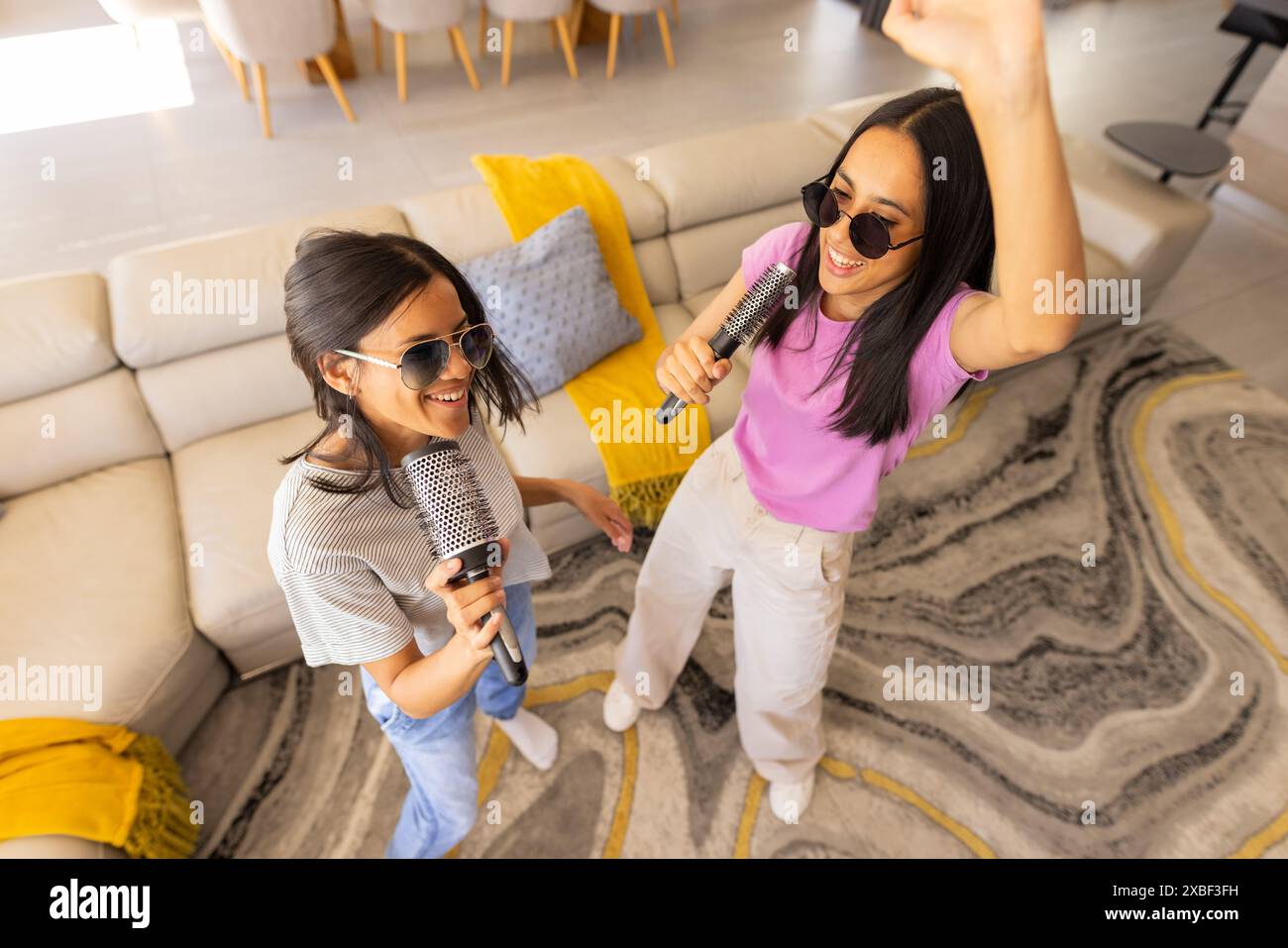 Two young biracial friends sing karaoke together, wearing sunglasses ...