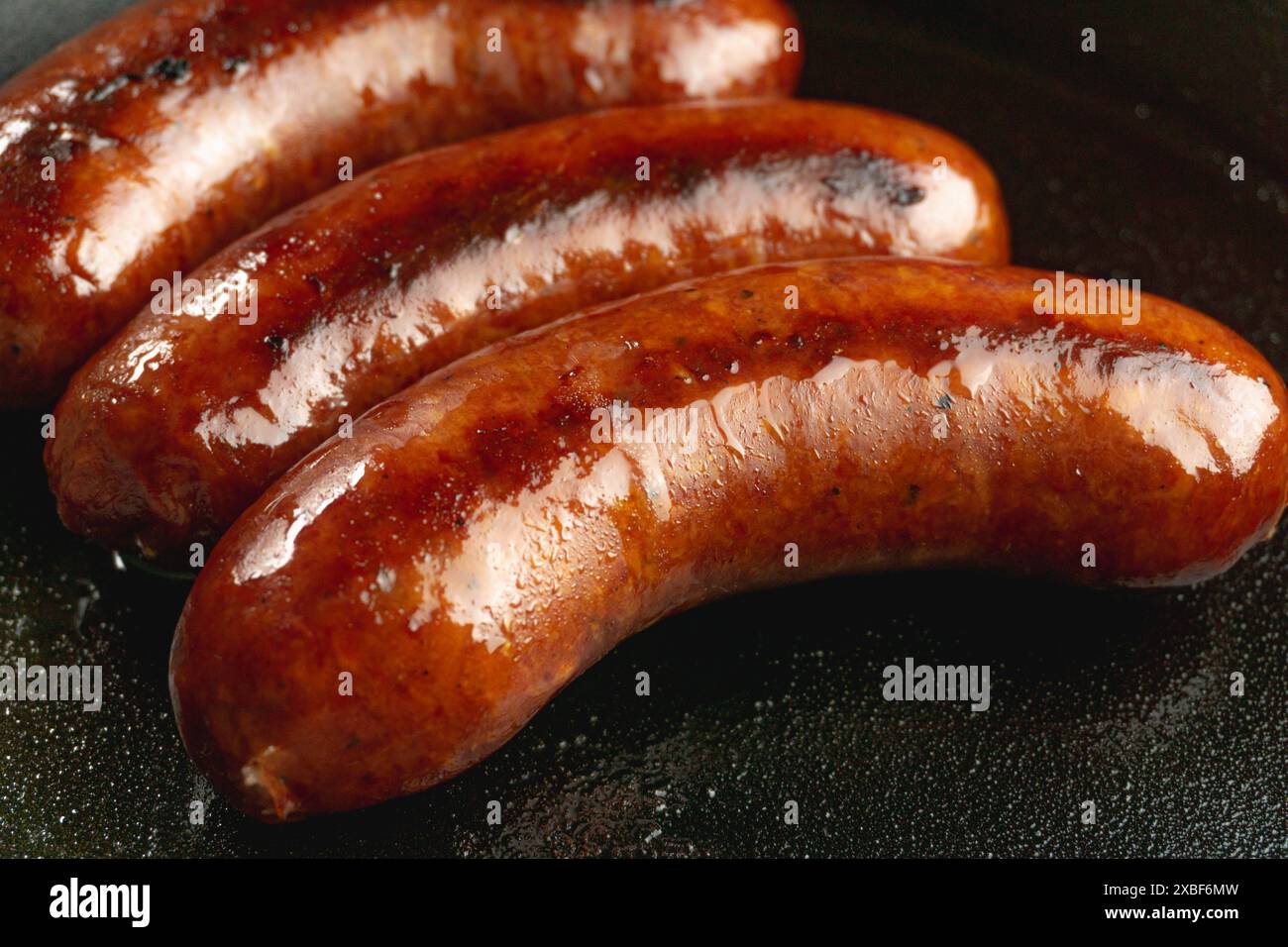 cured red juicy smoke beef sausage sear on cast iron skillet Stock Photo
