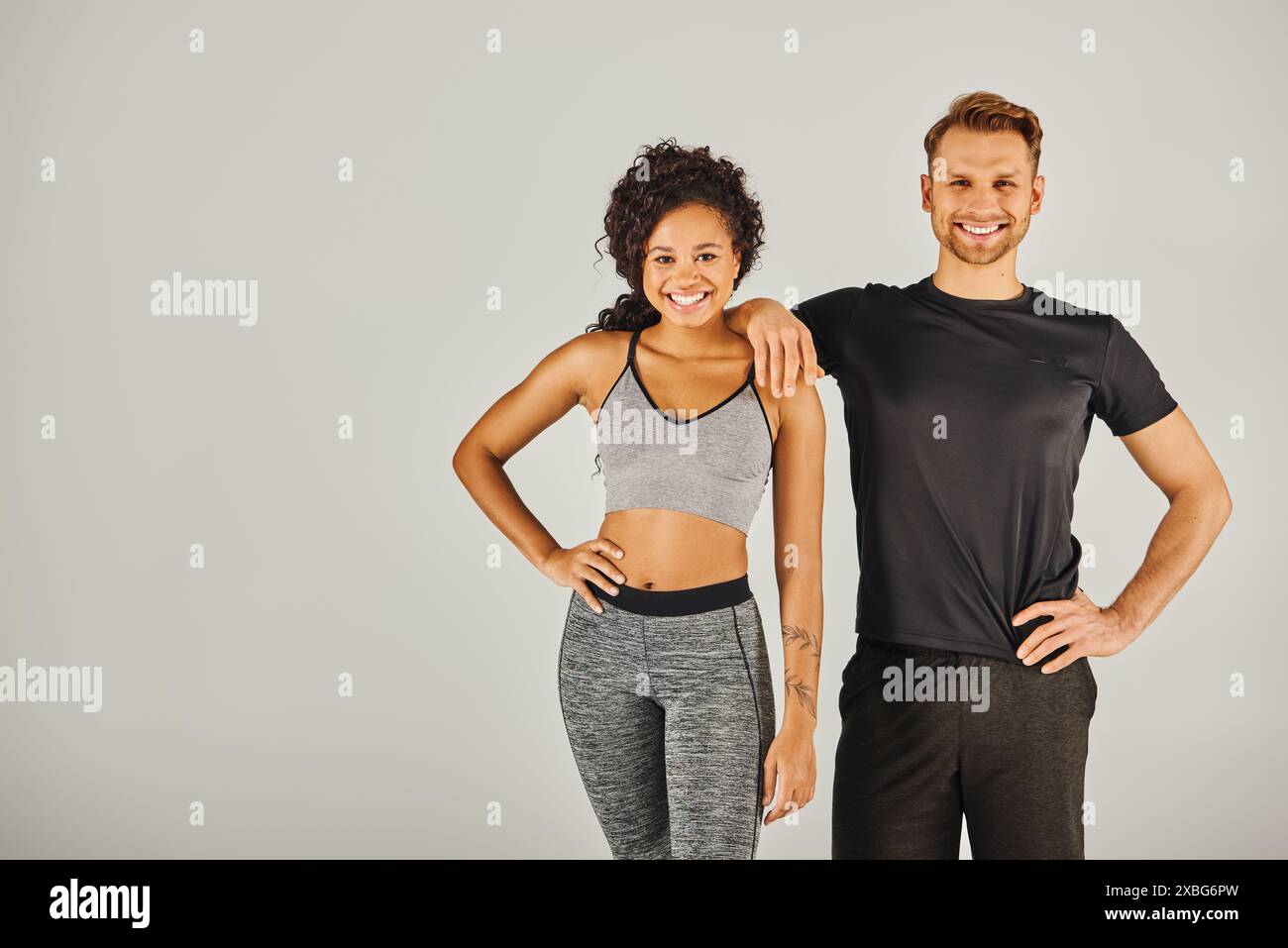 A young man and woman in sportswear strike a fashionable pose together ...
