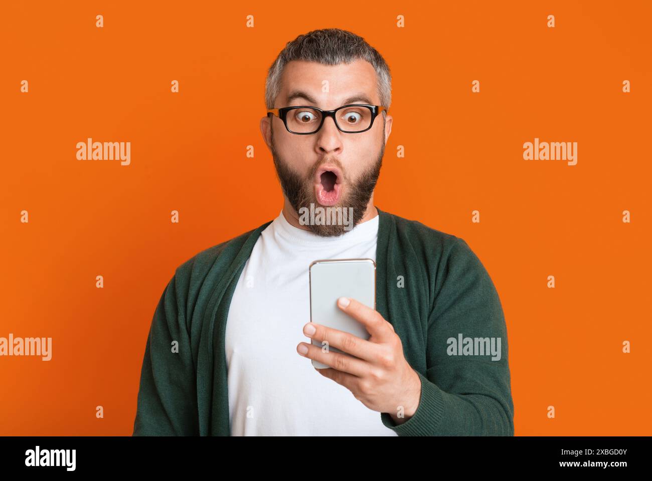Man With Beard Expressing Shock While Looking At Smartphone Stock Photo