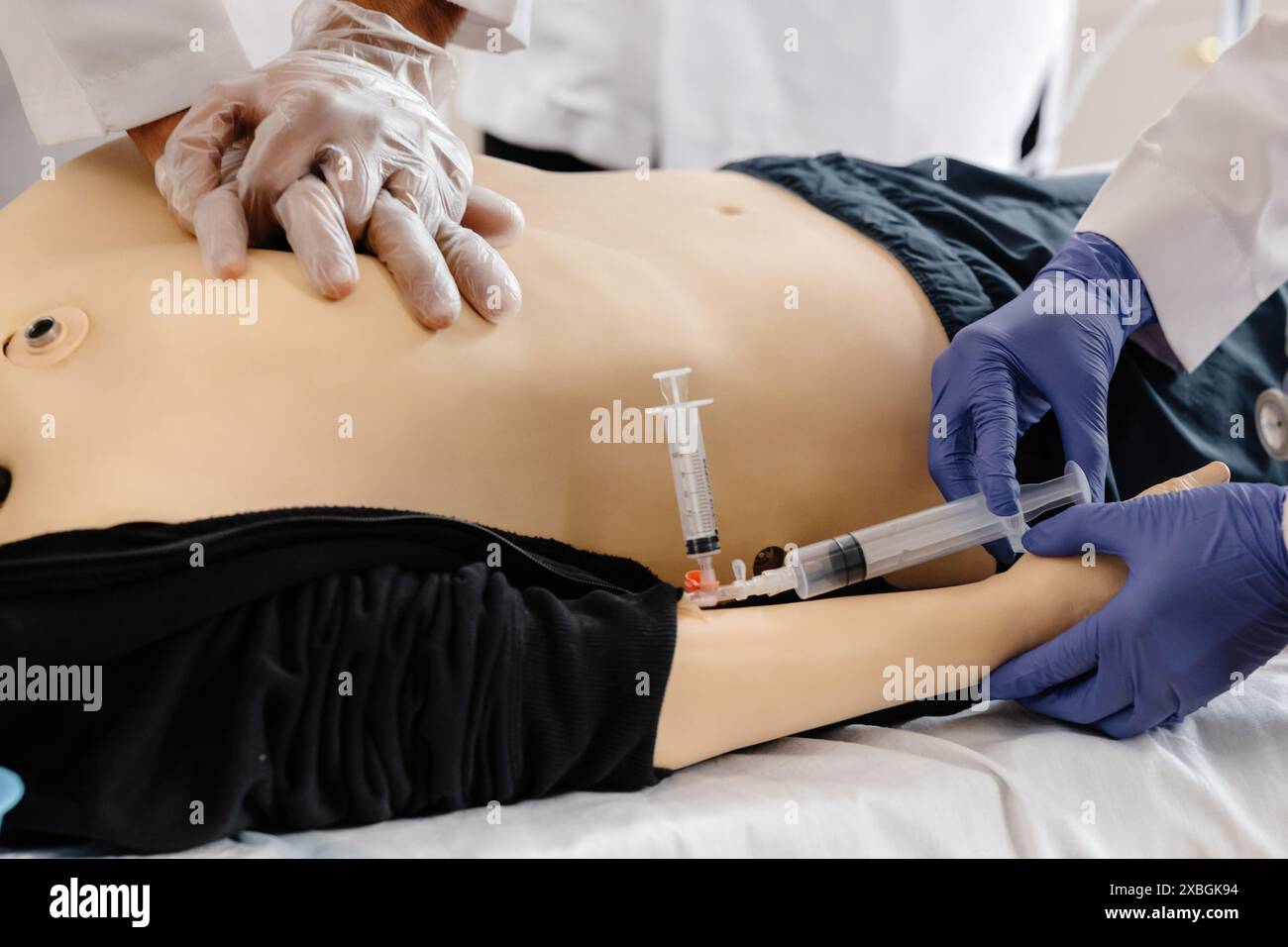 A medical student practices intravenous injection on a training dummy during a practical skills training session. Stock Photo