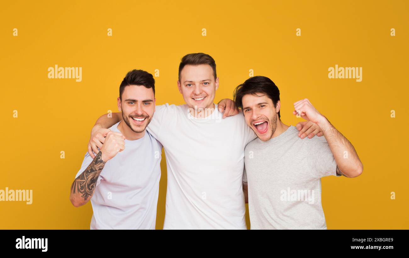 Three happy young men smiling on yellow Stock Photo