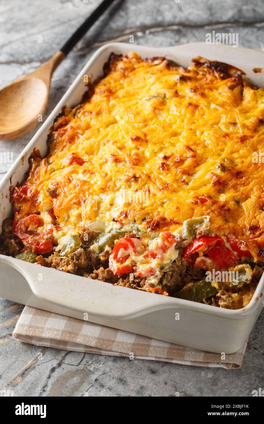 Delicious John Wayne casserole with beef, biscuits, cheese and vegetables close-up in a baking dish on the table. Vertical Stock Photo