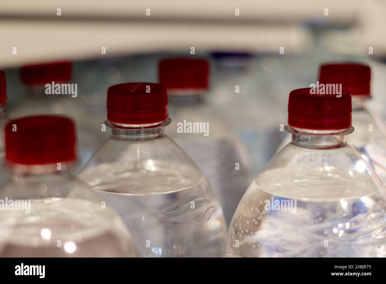 mineral water bottles with red cork caps are arranged in rows on the shelf Stock Photo