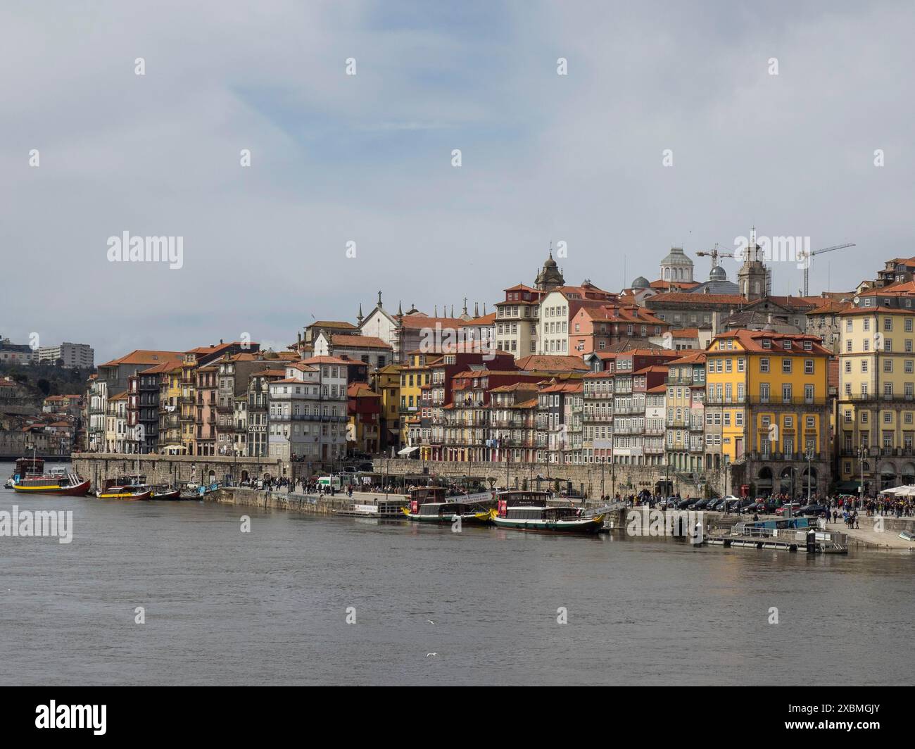 View of a riverside town with historic buildings and cloudy sky, yellow and red colours dominate the scene, Porto, Douro, Portugal Stock Photo
