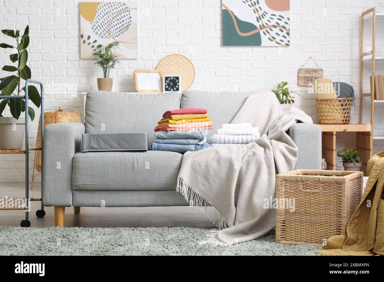 Stylish interior of modern living room with clean clothes on sofa Stock ...