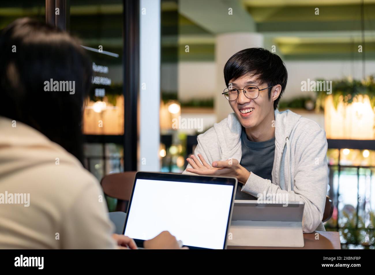A young, happy Asian male college student is talking with his friend ...