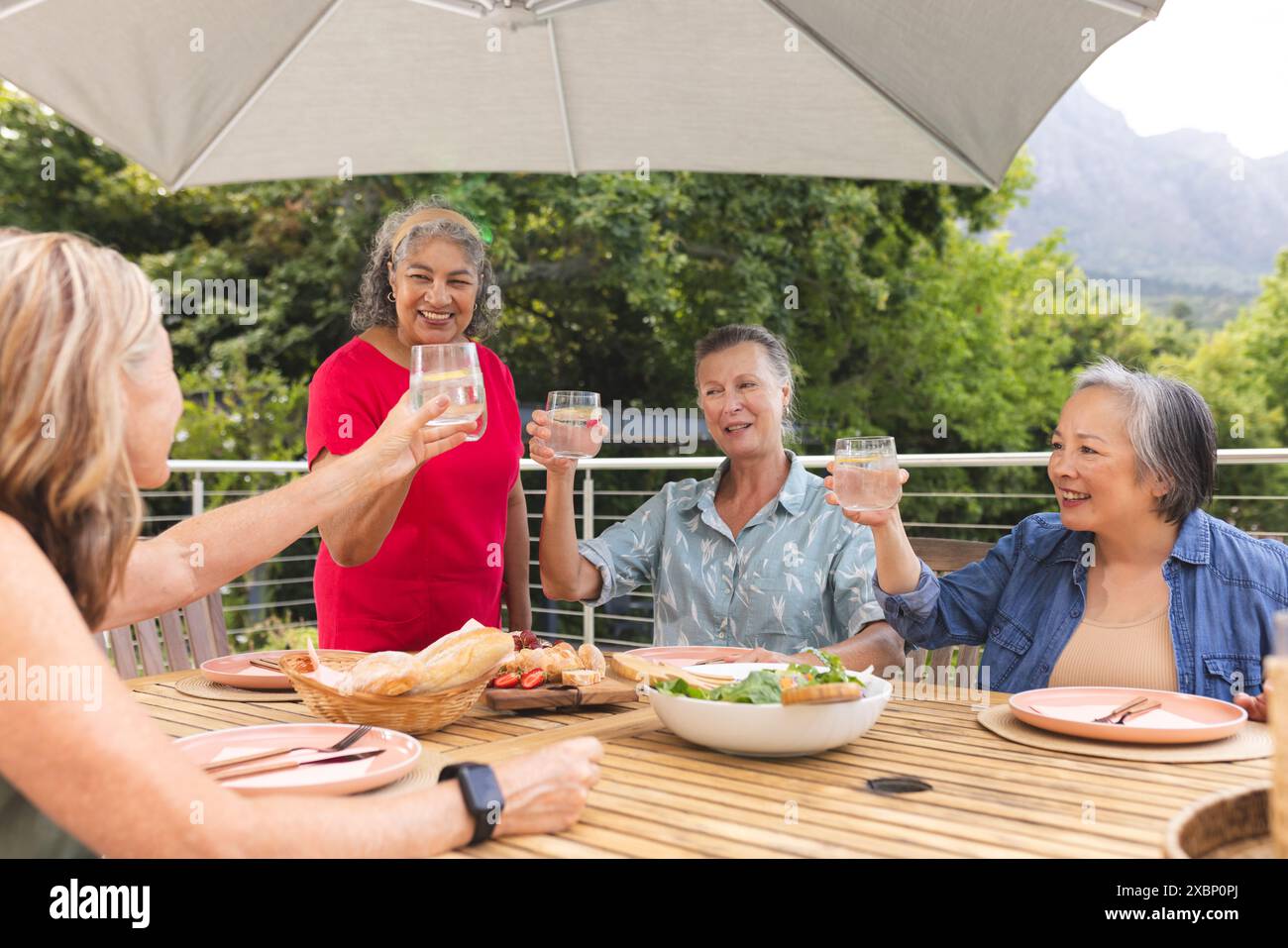 Group of diverse senior women enjoying drinks together at outdoor table Stock Photo