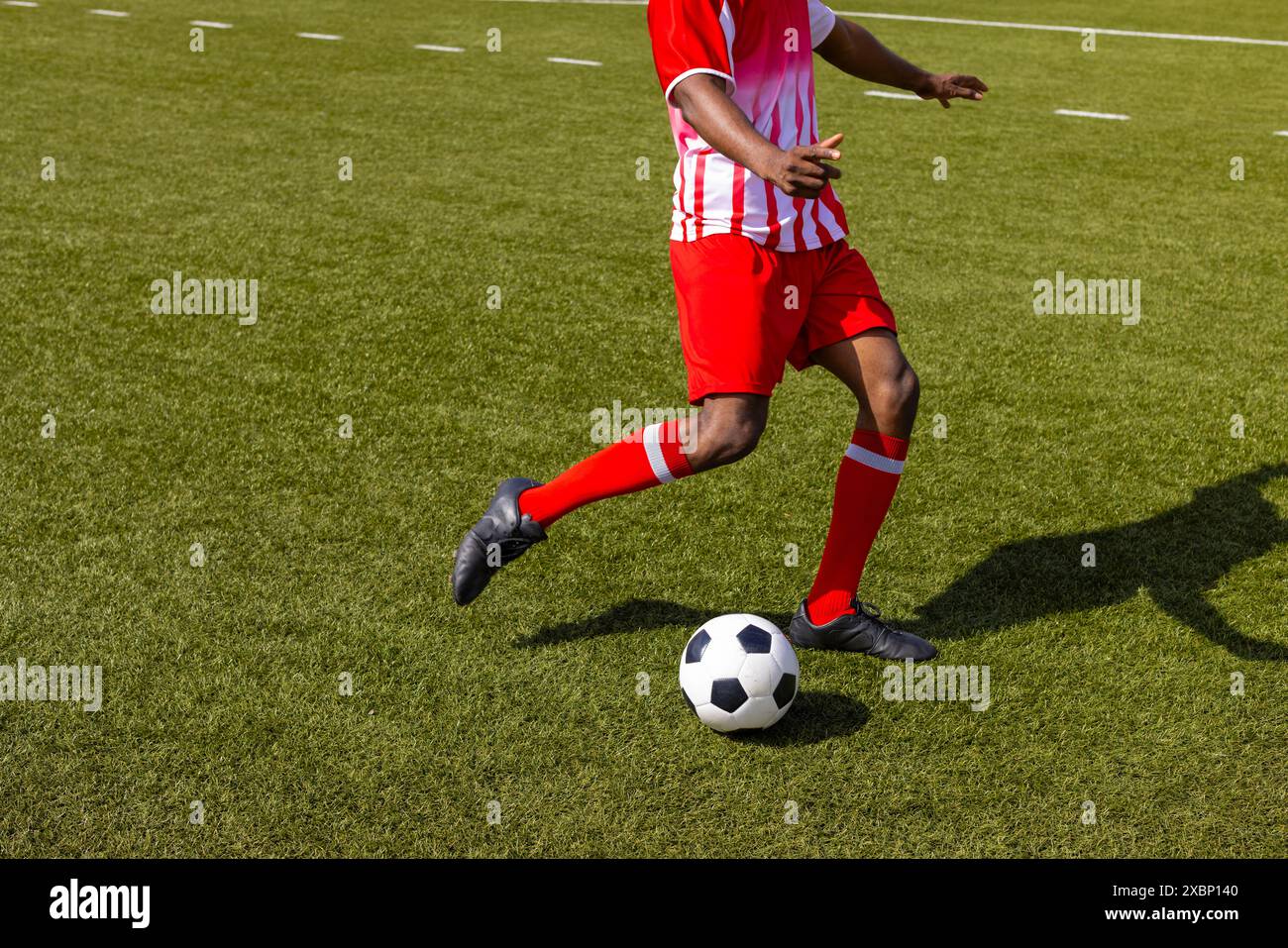 African American fitness trainer wearing red and white sportswear playing soccer, copy space Stock Photo