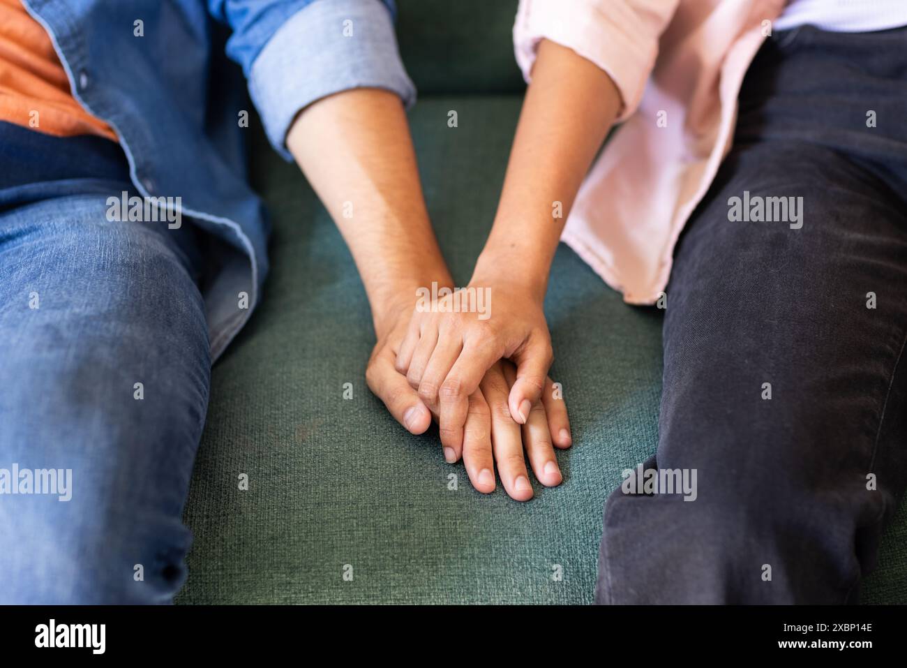 Diverse couple holding hands while sitting together Stock Photo
