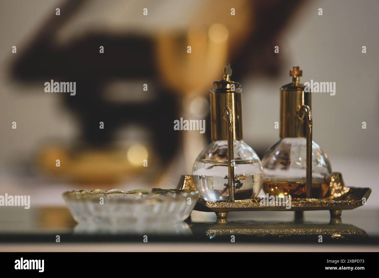 Two glass and brass containers holding holy water and chrism oil, essential for catholic baptism and confirmation ceremonies Stock Photo