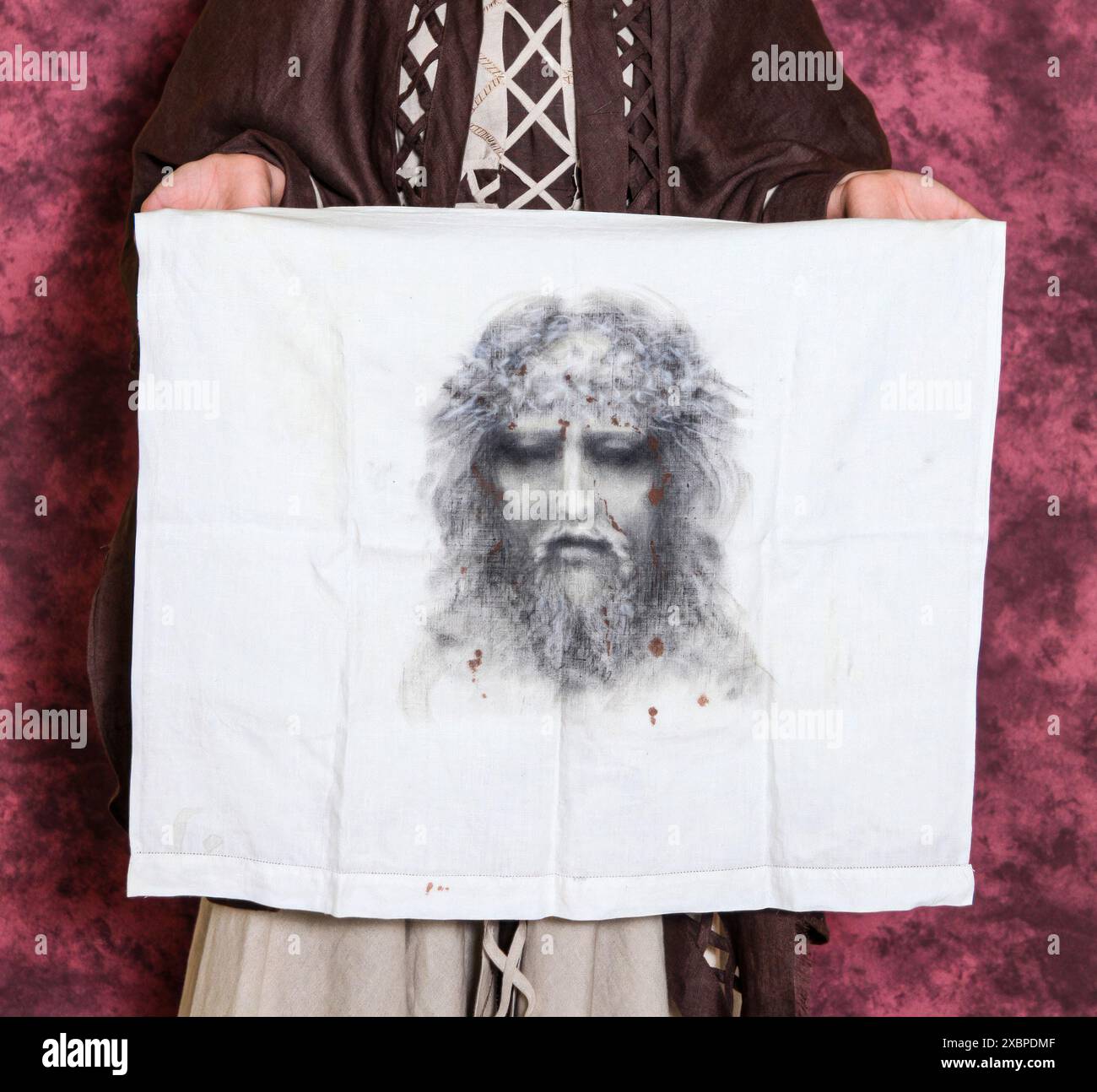 Monk wearing a brown tunic holding an ancient canvas with the face of jesus christ. Veronica with the Holy Shroud. Stock Photo