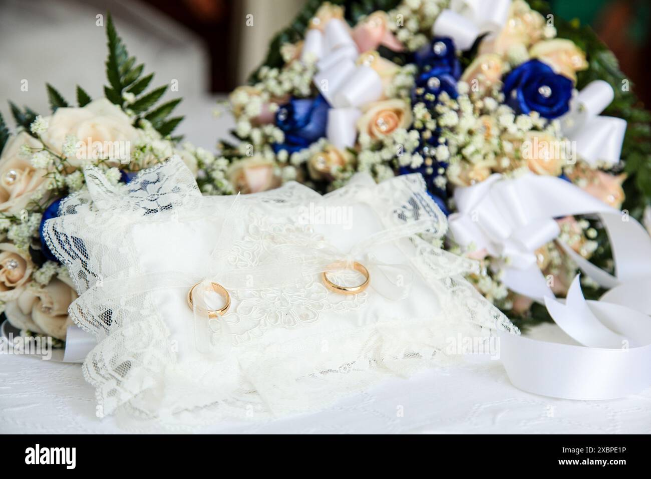 Two golden wedding bands rest on a delicate white lace pillow, representing the sacred bond of marriage between two individuals Stock Photo