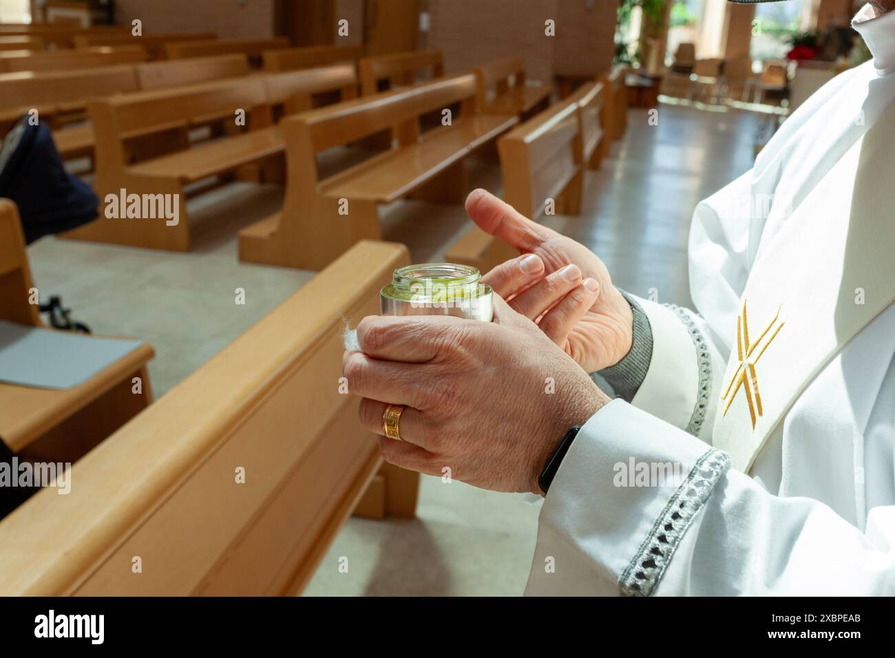 Priest wearing a stole and holding a silver jar containing the holy chrism oil, used for the sacraments Stock Photo