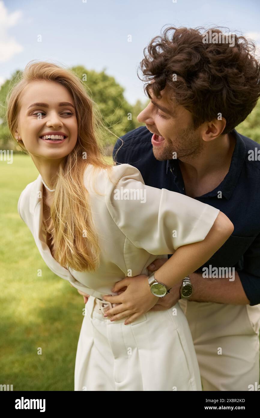 A beautiful young couple in elegant clothing pose gracefully in a lush green park, exuding a sense of old money style and rich people lifestyle. Stock Photo